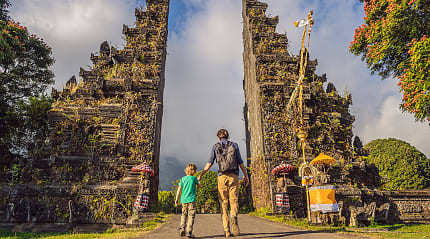 Father and son walking through traditional balinese gate Candi Bentar in Bali, Indonesia
