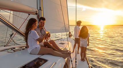 Young Hispanic brother and sister watching the sunset from luxury yacht with parents relaxing on deck enjoying togetherness