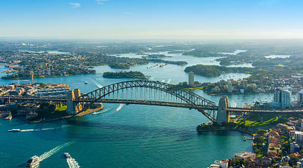 Sydney’s Harbour Bridge stretches proudly across sparkling, boat-filled waters.