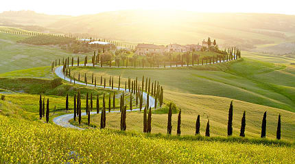 A farmhouse sitting in sunny fields in Tuscany.