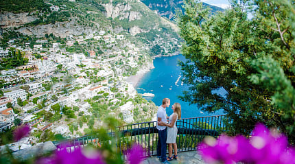 "Romantic couple embracing with a stunning view of Positano, Italy, on the Amalfi Coast overlooking the sea.