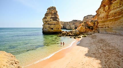 Couple in the water surrounded by limestone cliffs at Praia da Marinha in the Algarve