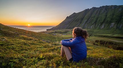 Hiker watching the midnight sun in Lofoten, Norway