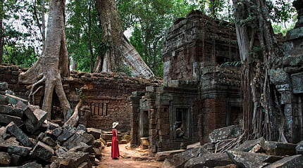 Woman in a red dress at Ta Prohm Temple ruins in Siem Reap, Cambodia