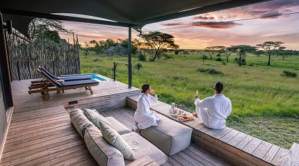 Coule watching the sunrise from the deck of their luxury tent Lemala Nanyukie in Serengeti National Park, Tanzania