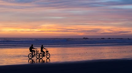 Couple biking on the beach at sunset in Costa Rica