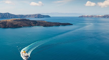 White ferry boat cruising through deep blue water near islands.