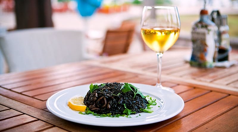 Black risotto with seafood and glass of white wine Black risotto with seafood and glass of white wine