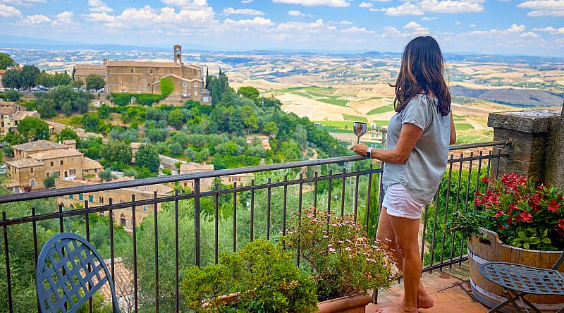 Woman enjoying a glass of wine and the view in Montalcino, Italy