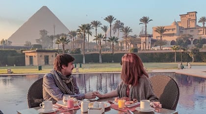 Couple enjoying breakfast with a view over the Pyramids of Giza in Egypt