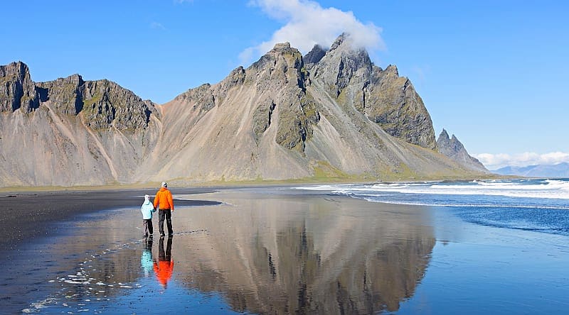 Stokksnes, Iceland Father and son, walking on black sand beach at beautiful Stokksnes peninsula, enjoying scenery of Vestrahorn mountains in iceland