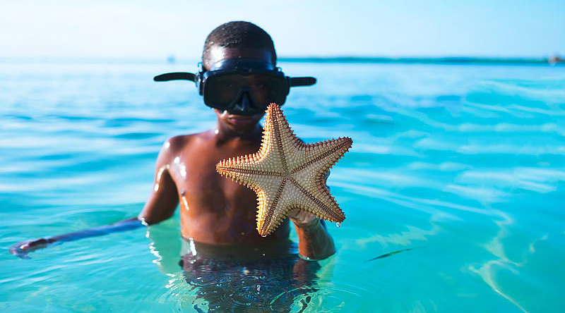 Young boy shows off a starfish he found while snorkeling in Belize