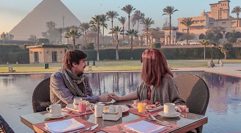 Couple enjoying breakfast with a view over the Pyramids of Giza in Egypt