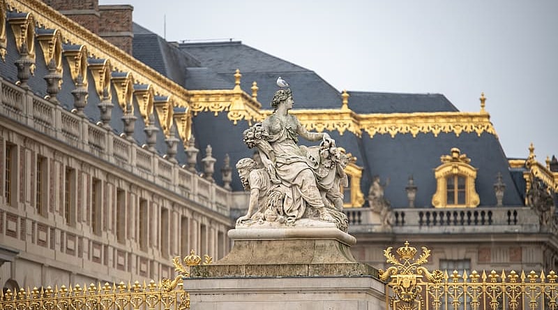 Statue and ornate architecture of Versailles in France.