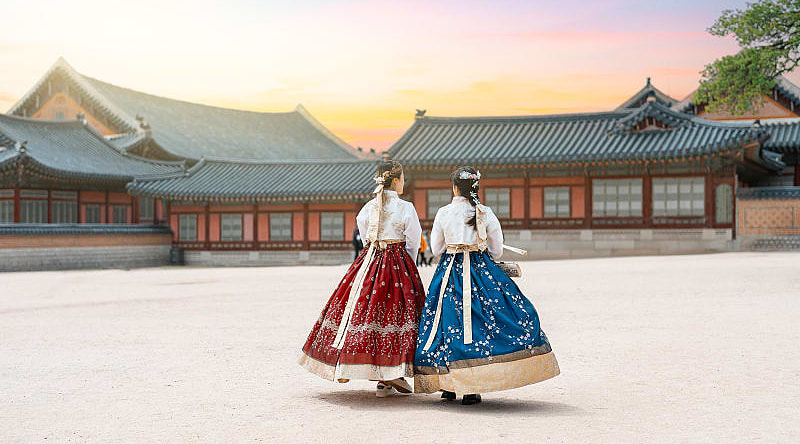 Women in hanbok stroll through the traditional-style homes in Seoul’s village.