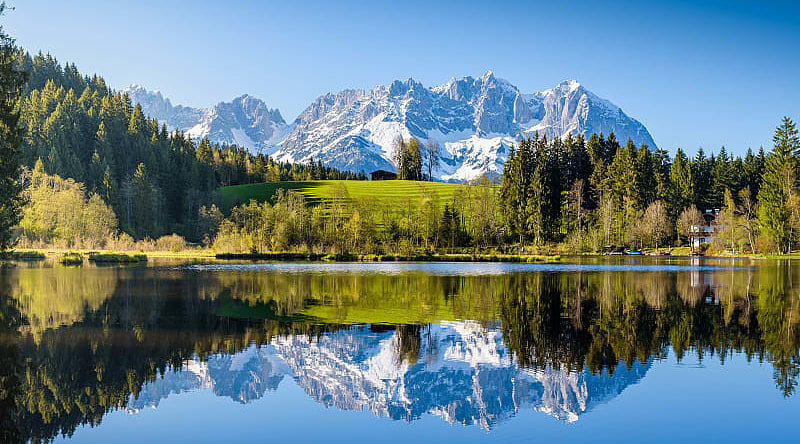Idyllic alpine scenery, snowy mountains mirroring in a small lake in Tyrol, Austria.
