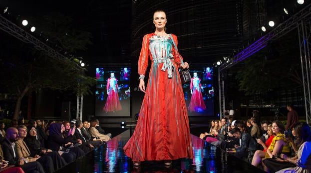 Runway model in a red dress at a fashion show. Credit: Ahmad Ardity