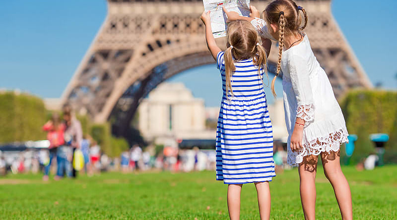 Little girls with a map of Paris on the background of the Eiffel tower, Paris