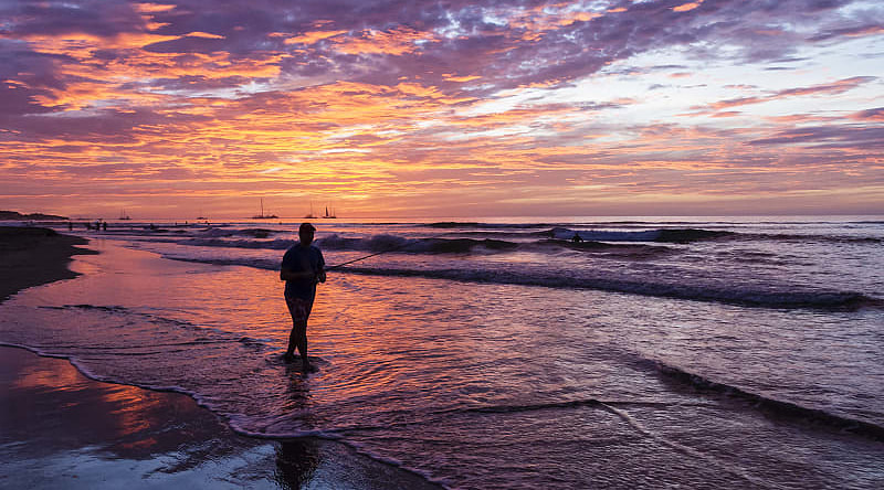 Fisherman silhouetted against the setting sun on Playa Tamarindo in Costa Rica