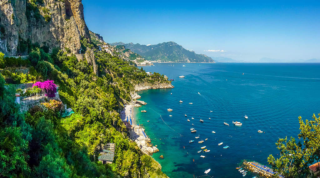 Postcard view of steep mountain cliffs and azure waters in the Amalfi Coast of Italy