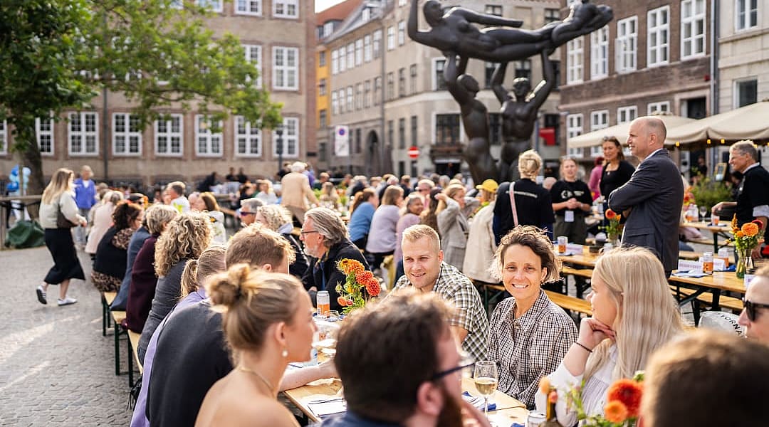 Outdoor dining scene at Copenhagen Cooking and Food Festival, people enjoying food in a lively square.