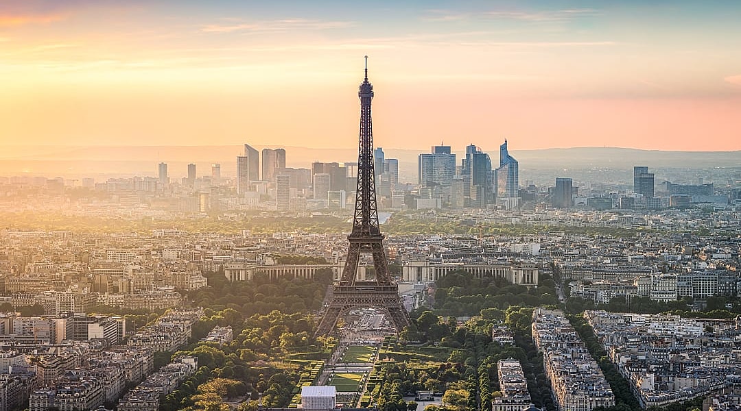 The Eiffel Tower stands tall over Paris with golden sunset hues.