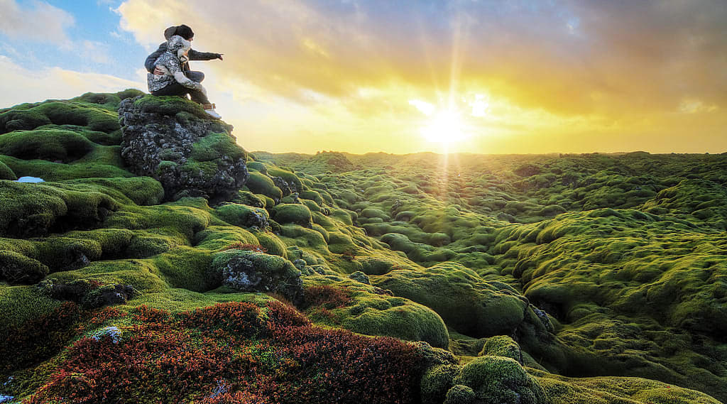 Couple watching the sunrise over Eldhraun lava field in Southern Iceland