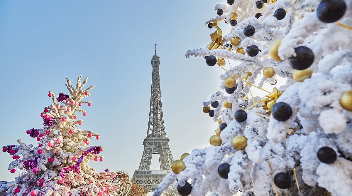 Snow-covered Christmas trees decorated with ornaments with the Eiffel Tower in the background, capturing the festive holiday in Paris, France