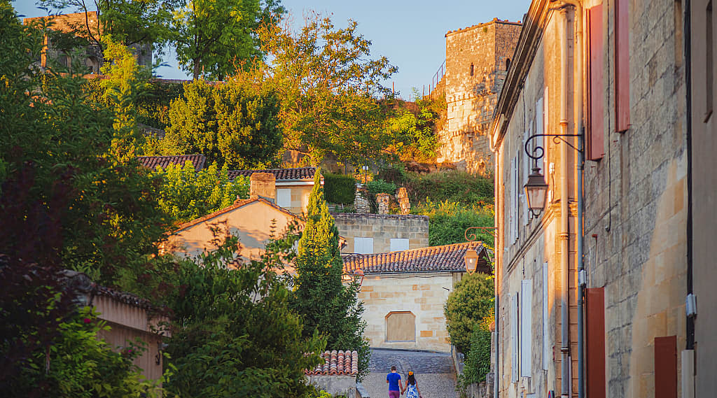 A couple hold hands strolling through the romantic village of Saint-Émilion in Bordeaux, France