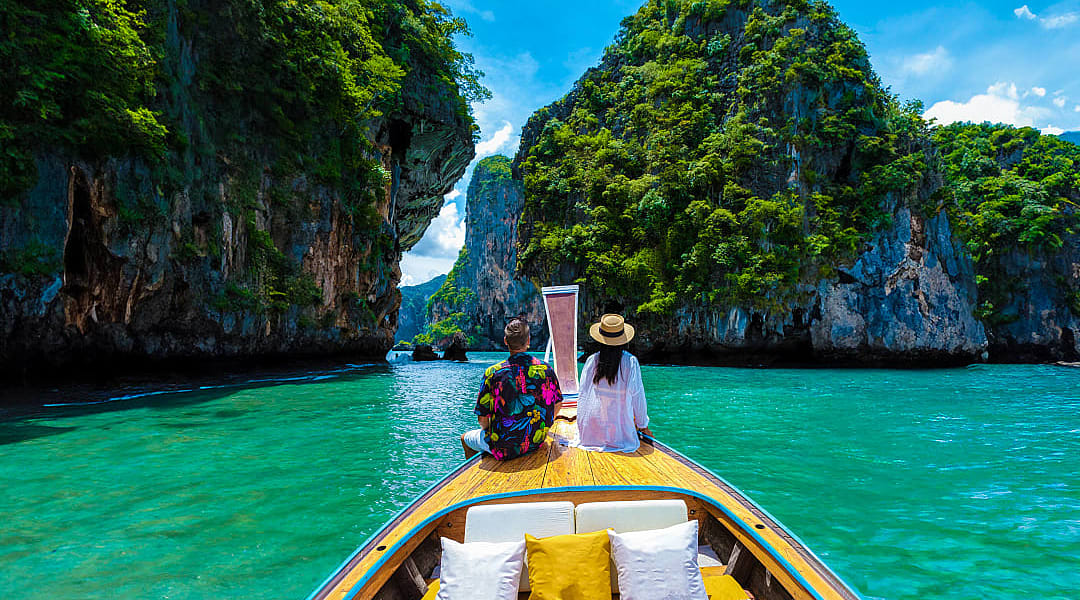 Couple on a traditional boat exploring turquoise waters and limestone cliffs in Krabi, Thailand