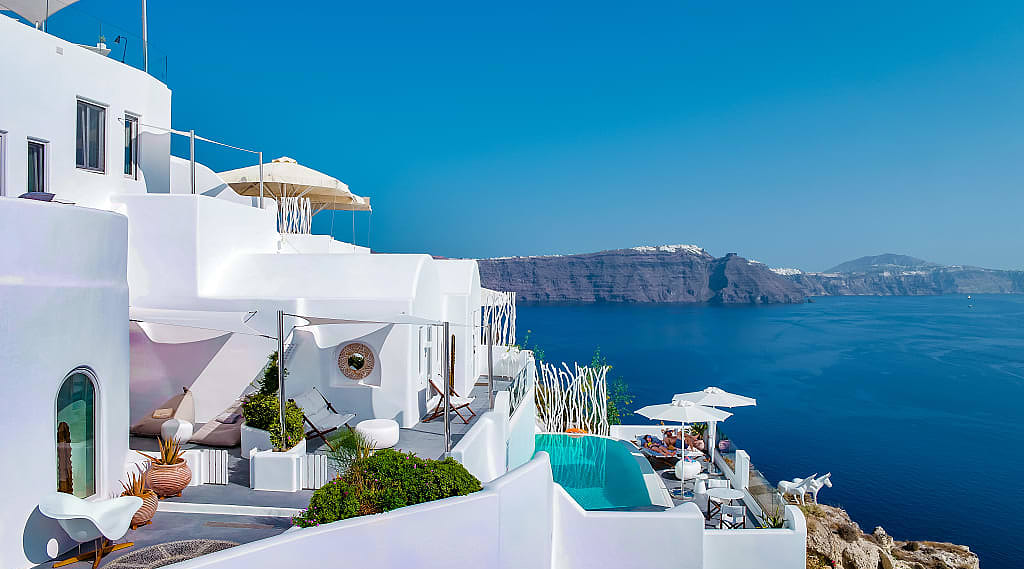 Couple lounging poolside at boutique luxury hotel in Santorini, Greece