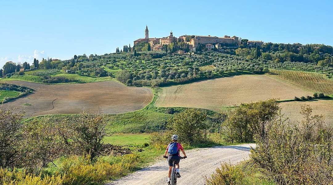 Woman biking on dirt road towards Pienza in Tuscany, Italy
