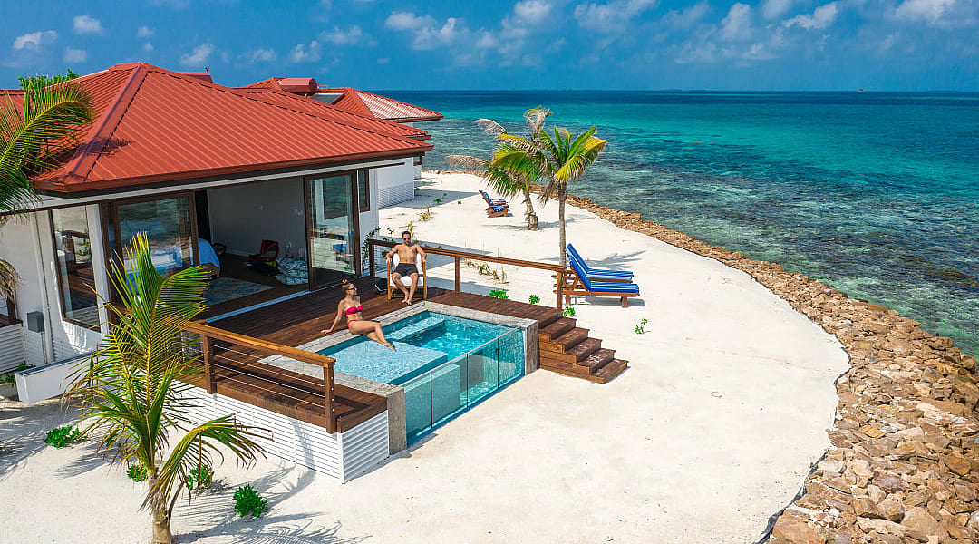 Couple at a luxury beachfront villa with a private pool, ocean view, and palm trees in Belzie