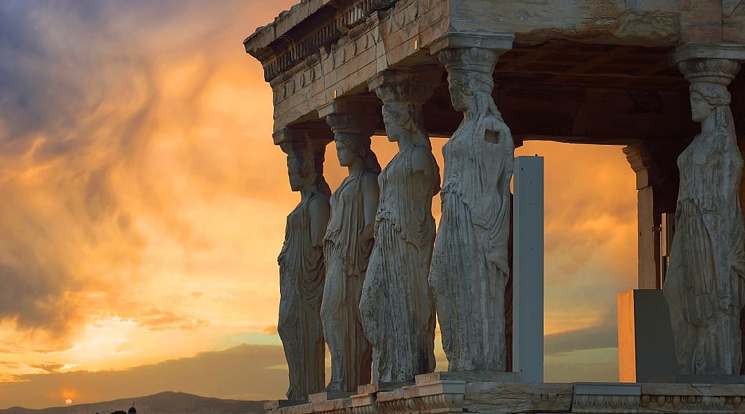 Caryatid statues support Erechtheion porch at sunset in Athens.