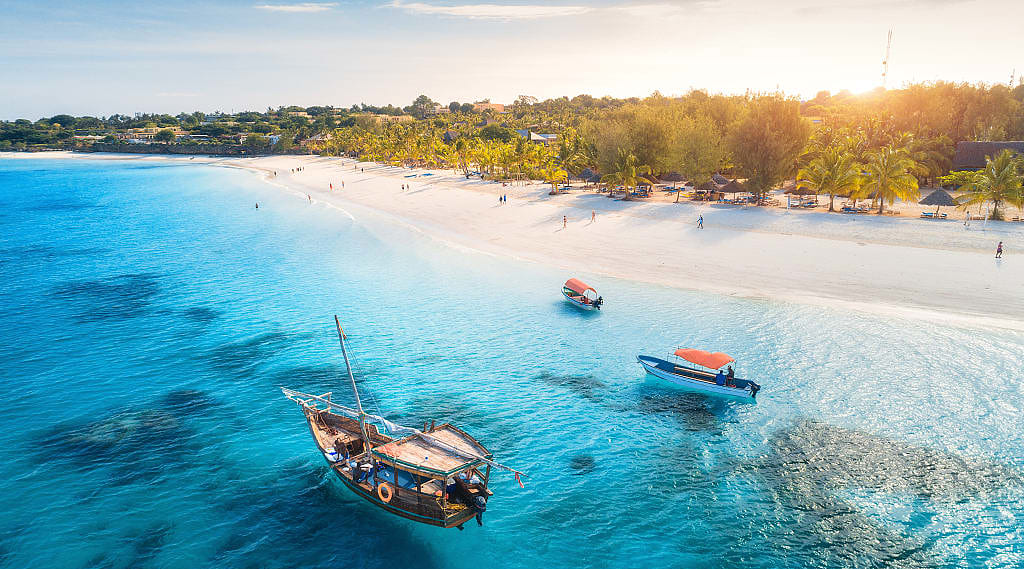 Boats on tropical sea coast with sandy beach at sunset in Tanzania, Zanzibar on the continent of Africa