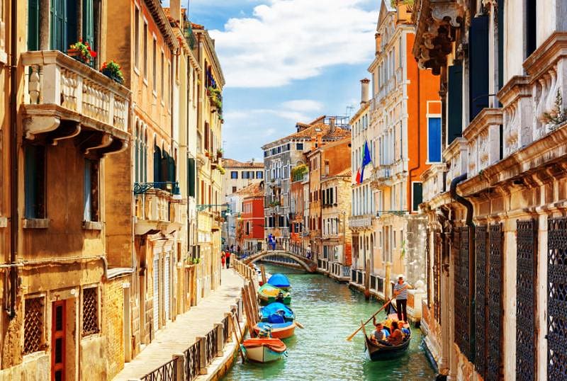 Riding a gondola through a narrow canal - an essential experience on a trip to Venice