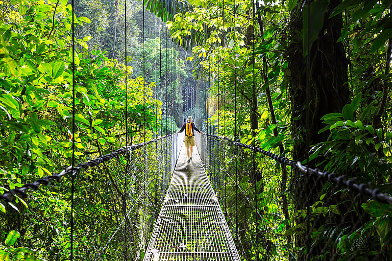 Tourist hiking across hanging bridge in Costa Rica