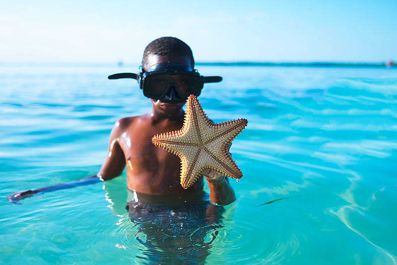 Young boy shows off a starfish he found while snorkeling in Belize