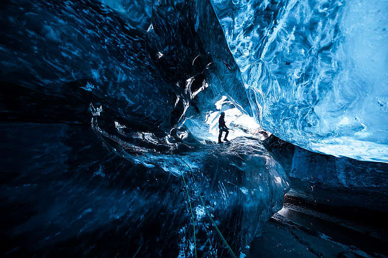 Mountain climber standing inside ice cave glacier