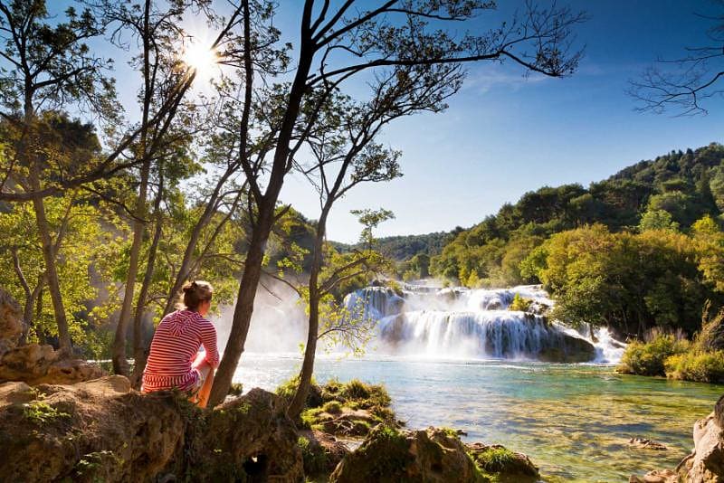 Croatia Tour for Seniors: Sophistication and Adventure Woman traveler relaxing and viewing the waterfalls in Krka National Park Park, Croatia
