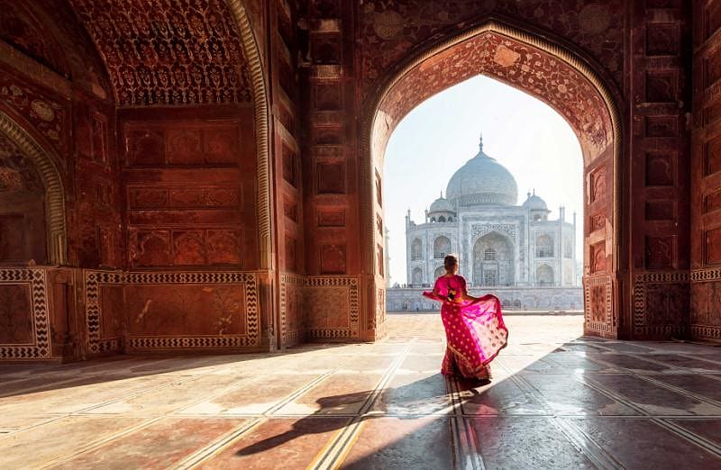 Woman in red sari admiring the Taj Mahal in Agra India