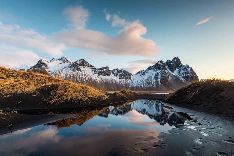 Vesturhorn Mountain reflects over clear waters.
