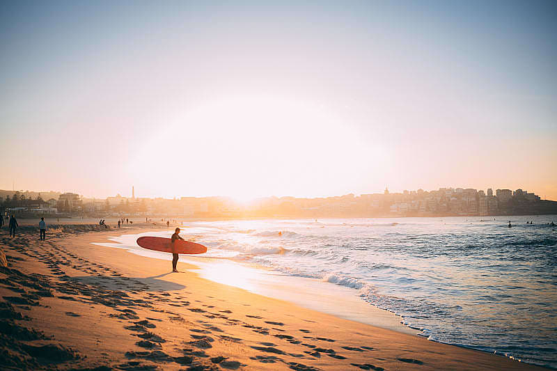 Surfer at sunset on the beach in Bondi, Australia