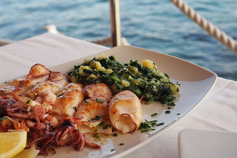 Fried squid with boiled potatoes and Swiss chard. Traditional Croatian cuisine, Rovinj