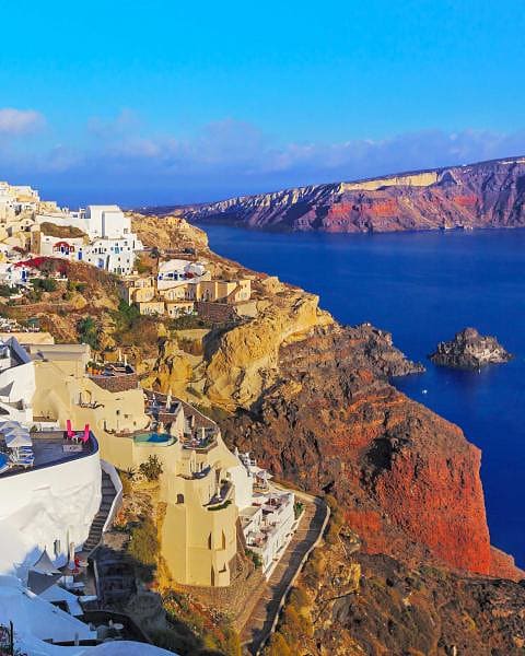 buildings on orange cliffs overlooking the sea on a beautiful day
