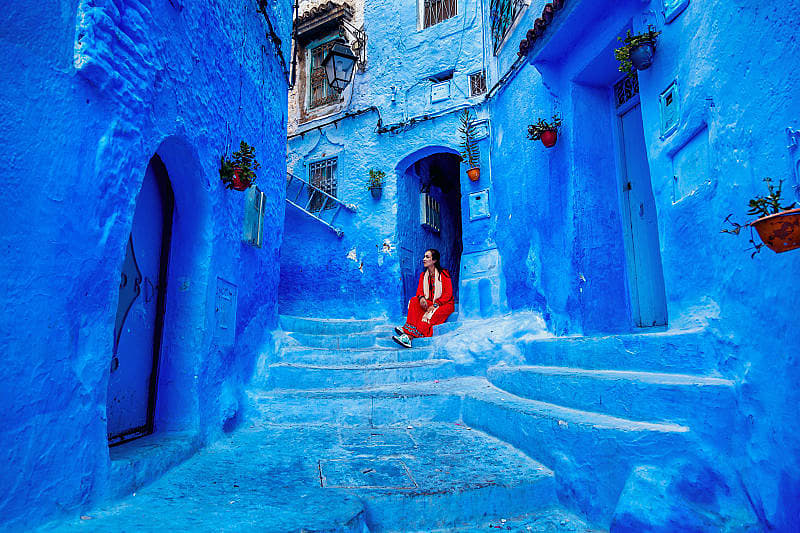 Imperial Cities & Sahara Desert Tour of Morocco Tourist sitting steps in Chefchaouen, the Blue City of Morocco