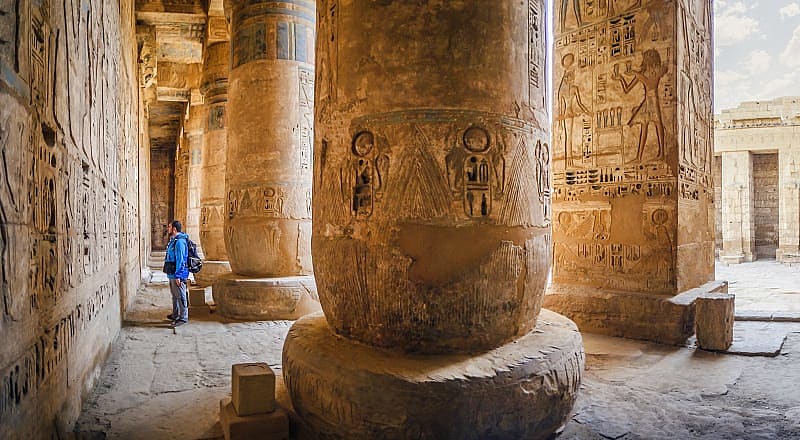Traveler viewing hieroglyphs on the walls of the Temple of Medinet Habu in Egypt