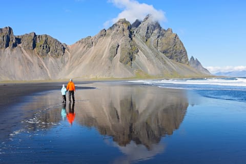 Father and son on the black sand beach of Stokksnes with Vestrahorn mountain in Iceland