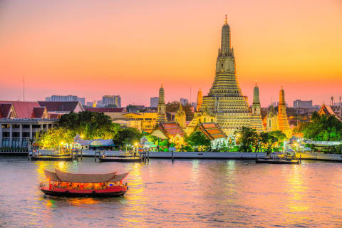 Boat on the river passing in front of Wat Arun at dawn in Bangkok, Thailand