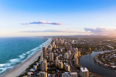 Long strand of beach sandy beach with city skyscrapers and the Nerang River on Australias Gold Coast